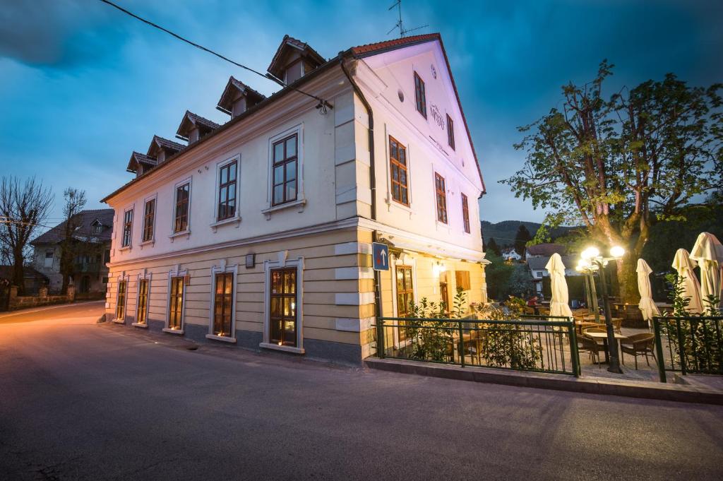 a white building with windows and a fence at Hotel Pri mostu in Dolenjske Toplice