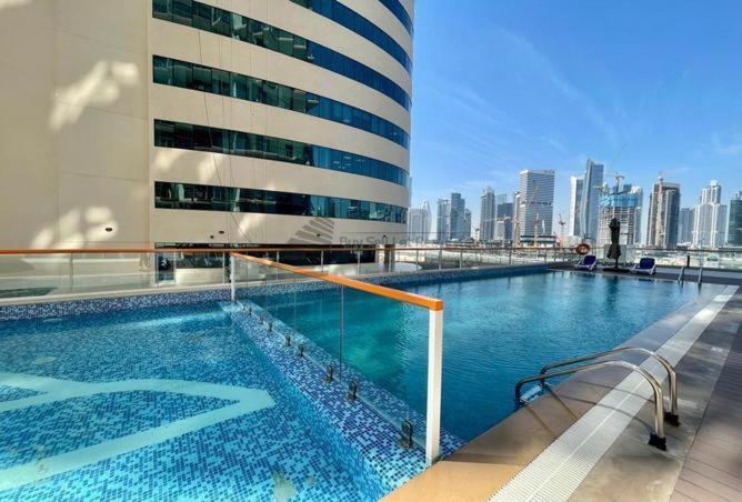 una gran piscina con vistas al perfil urbano de fondo en Dubai Canal Burj khalifa view 2bedroom apartment, en Al Ḩamīdīyah