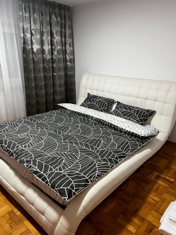 a bed with black and white sheets and pillows at Mona Apartment Taxi#Airport #PARKING#BUCHAREST#THERME in Otopeni