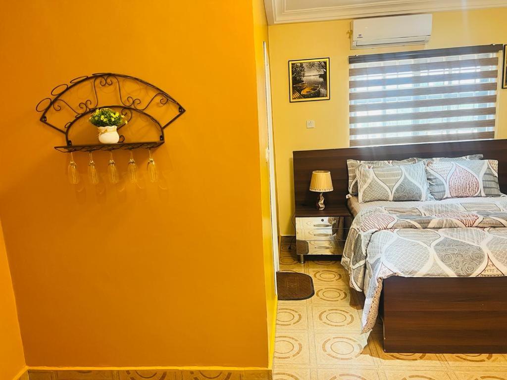 - une chambre avec un lit et un mur jaune dans l'établissement AJ Homes, à Ashalebotwe