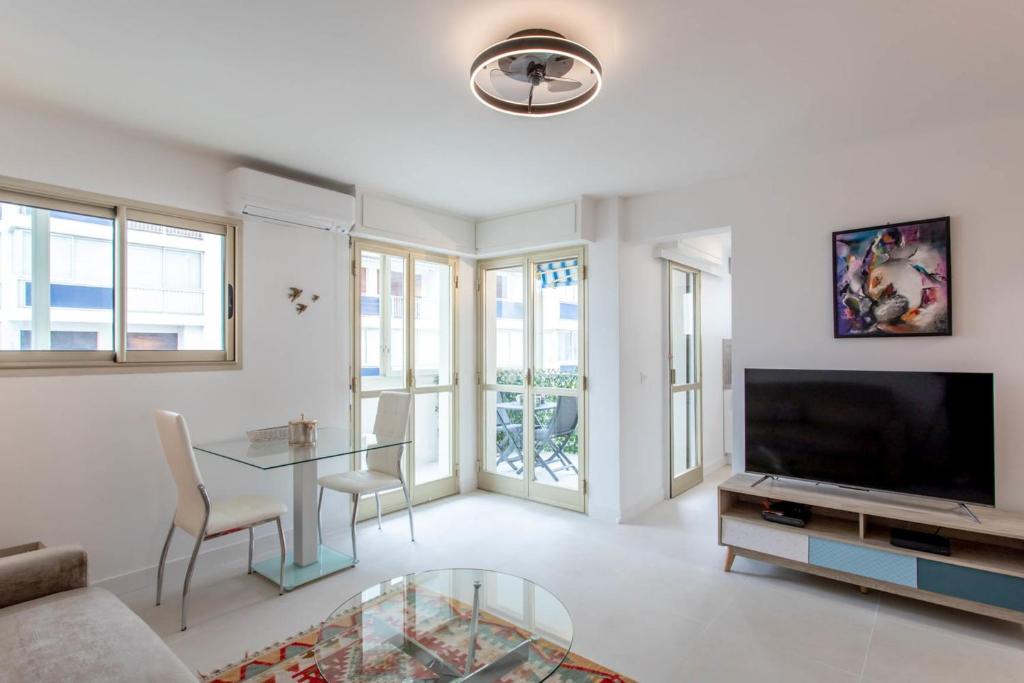 uma sala de estar com uma televisão e uma mesa e cadeiras em Palm Beach Hippocampe - Beautiful Studio apartment near by Sea em Cannes
