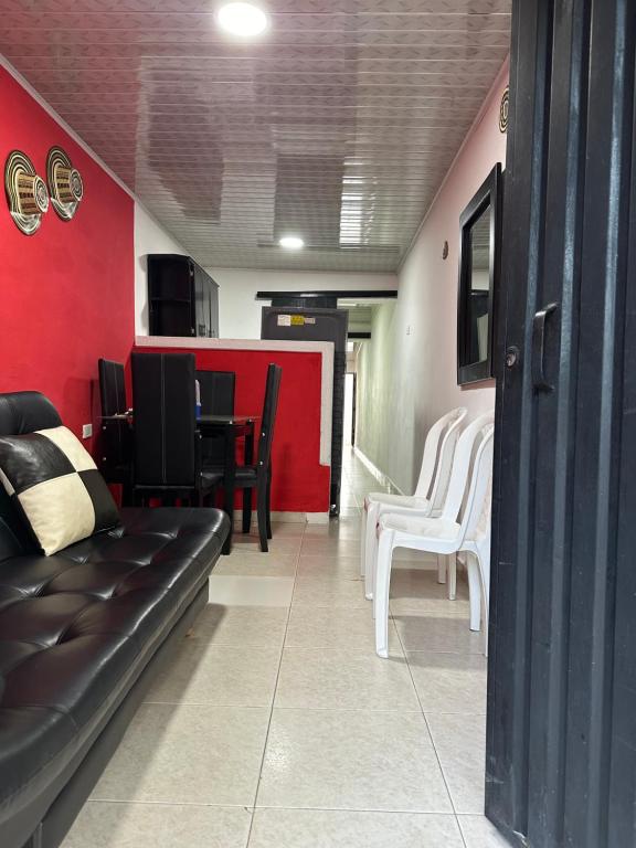 uma sala de estar com um sofá preto e uma parede vermelha em Alojamiento Turístico MARY cerca CC Mayales em Valledupar