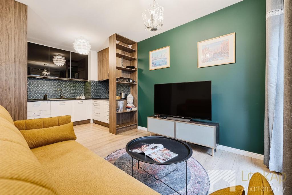 un salon avec un canapé et une télévision dans l'établissement Fuzja IV by LookAp, à Łódź