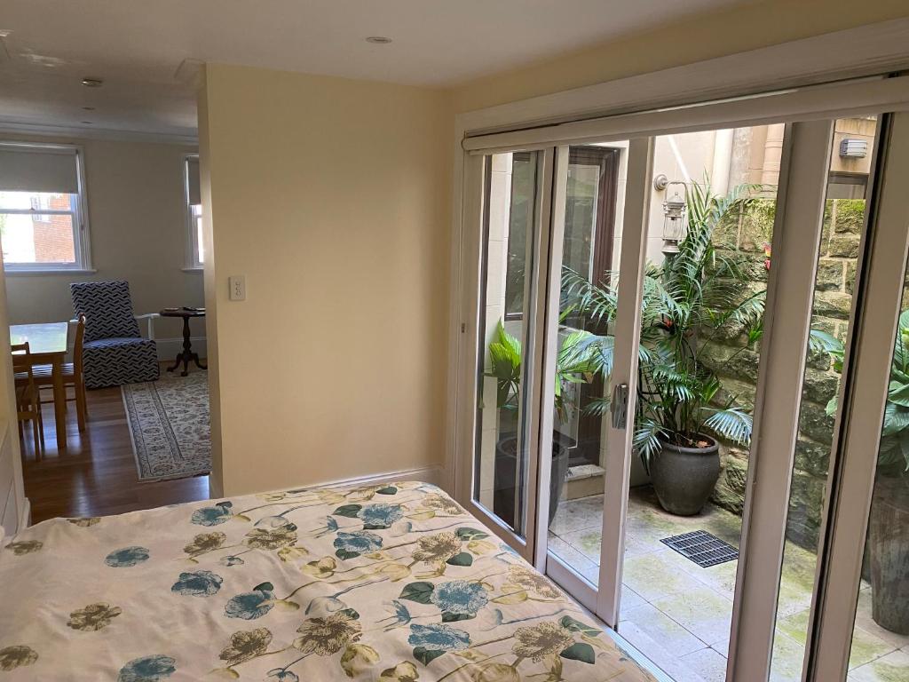 a room with a bed and glass doors with a patio at Garden flat, NORTH SYDNEY in Sydney
