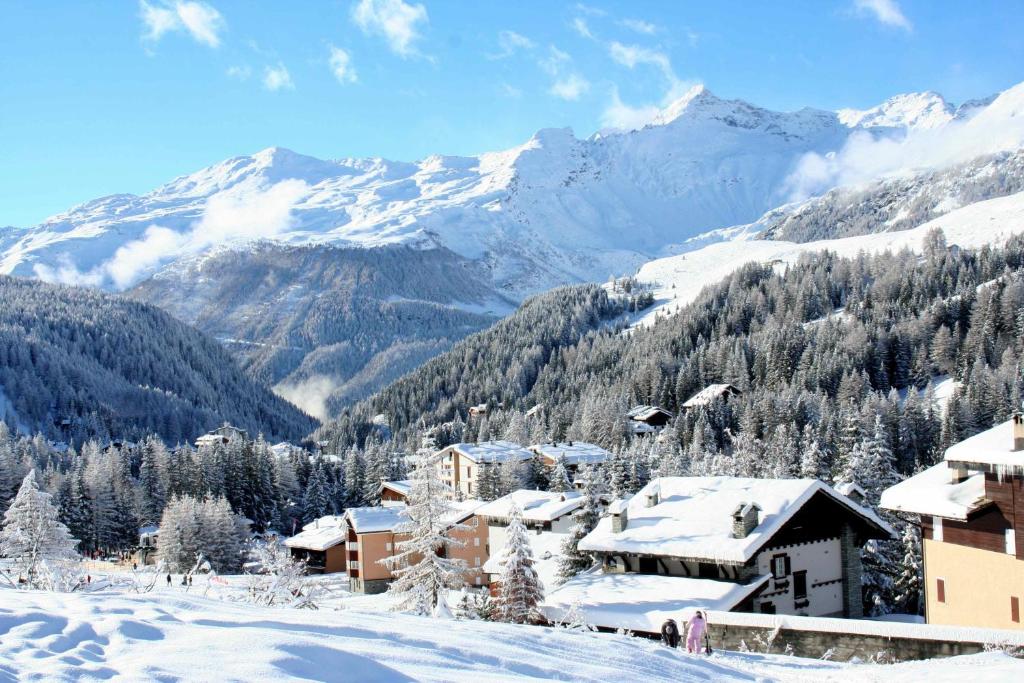 a snow covered village with mountains in the background at Piazzagemelliholiday in Madesimo