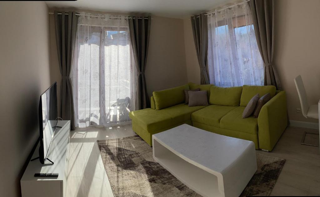 a living room with a green couch and a tv at 2 bed 2 bath, 4 min walk to slope, Predela2, Bansko in Bansko