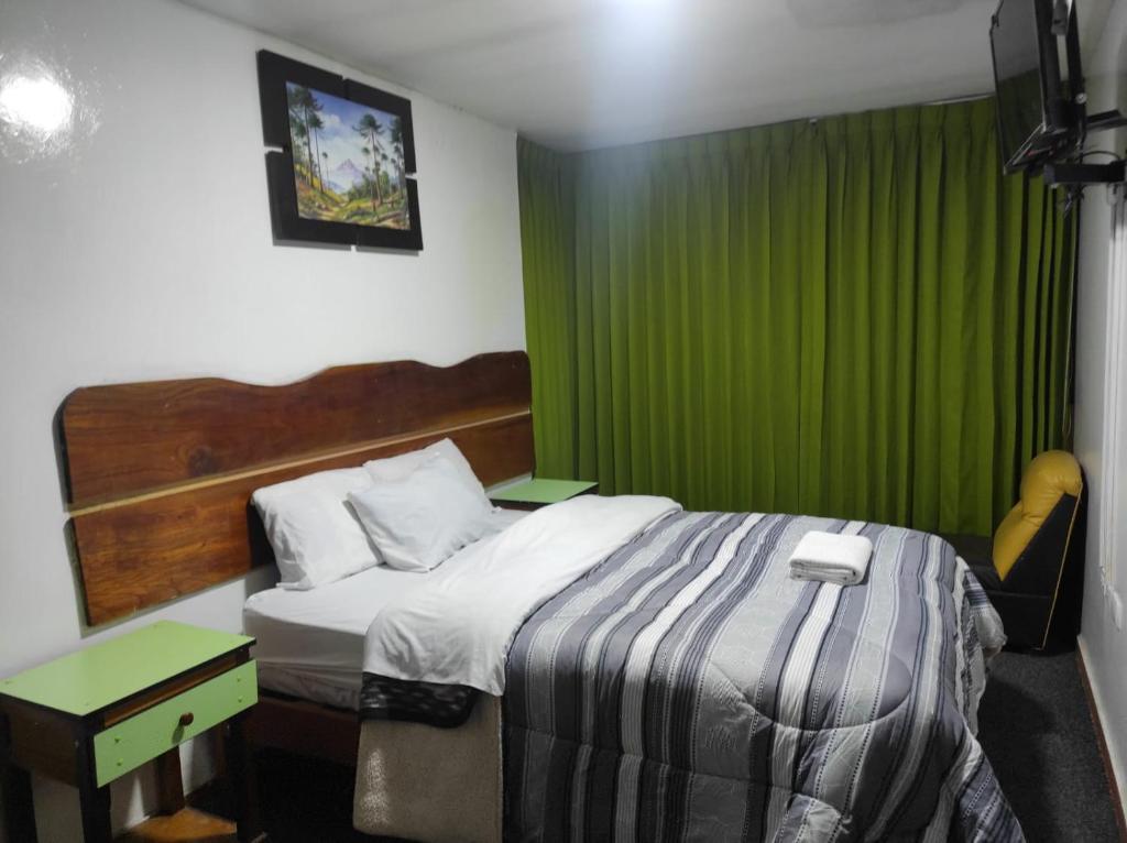 een slaapkamer met een bed en een groen gordijn bij Sierra Verde - Muy Céntrico Hs in Huancayo