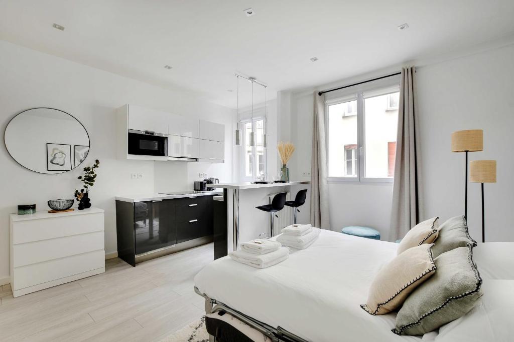 Cette chambre blanche dispose d'un lit et d'une cuisine. dans l'établissement Magnificent studio - 2P - Ternes-Arc de Triomphe, à Paris