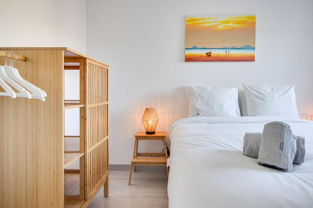 een slaapkamer met een wit bed en een houten kast bij Lovely 3BD 150m Beach Ocean View AC Wi-Fi Balcony in Albufeira