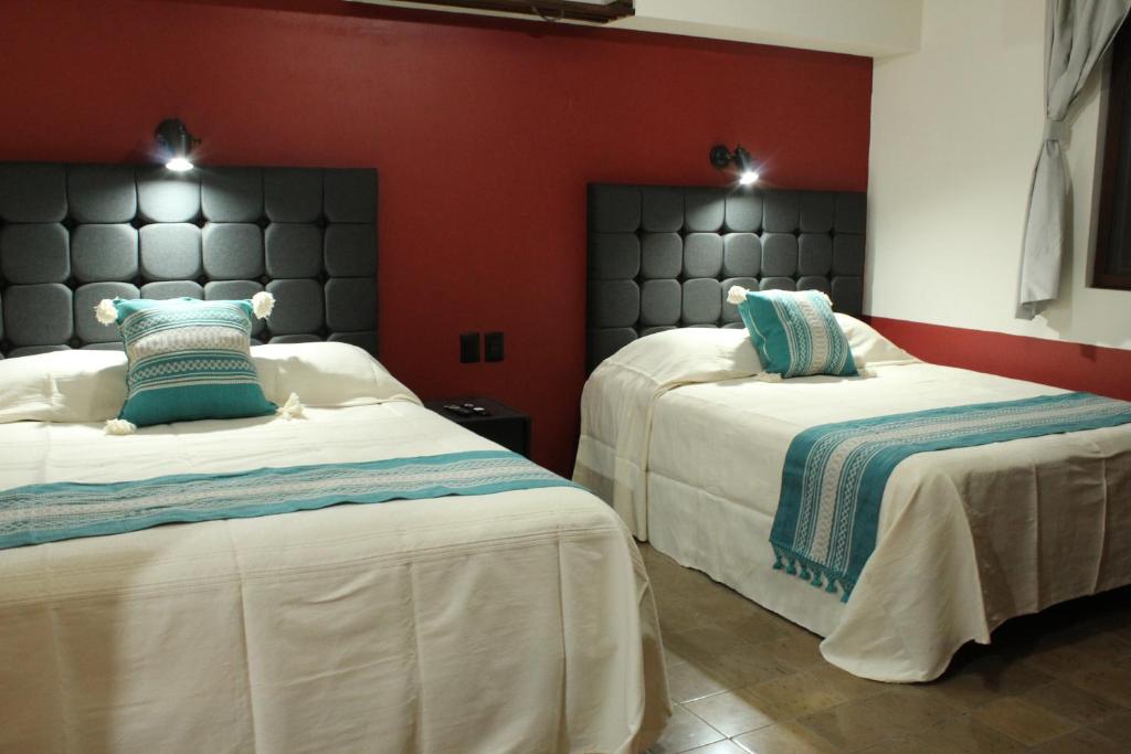 a bedroom with two beds and a red wall at Lidia Anturios in Oaxaca City