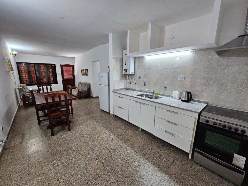 eine Küche mit weißen Schränken, einer Spüle und einem Tisch in der Unterkunft Departamento zona norte in La Rioja