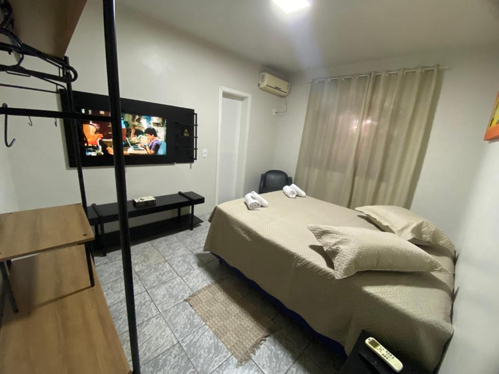 - une chambre avec un lit et une télévision à écran plat dans l'établissement Espaço confortável no centro da cidade, à Foz do Iguaçu