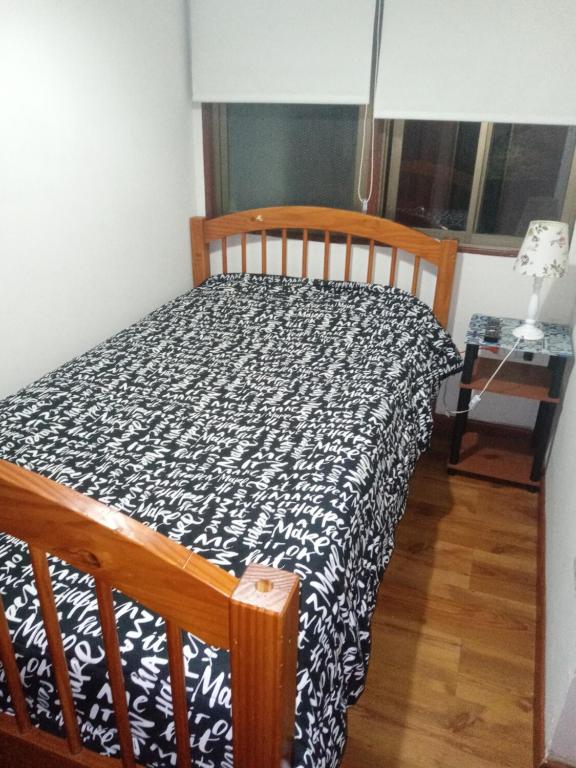łóżko z czarno-białą kołdrą w pokoju w obiekcie Habitación casa familia w mieście La Serena