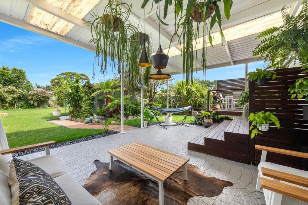a patio with a wooden table and some plants at Villa Del Mar - Belle Escapes Jervis Bay in Vincentia