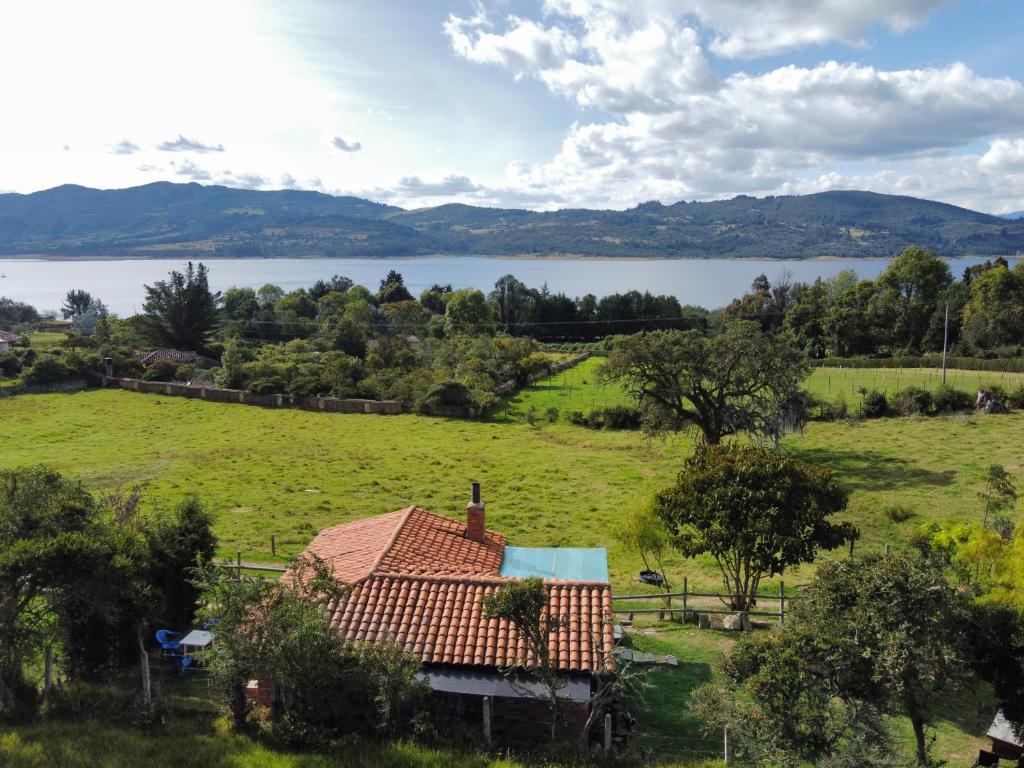 a house in a field with a lake in the background at Rancho New Life Guatavita in Guatavita