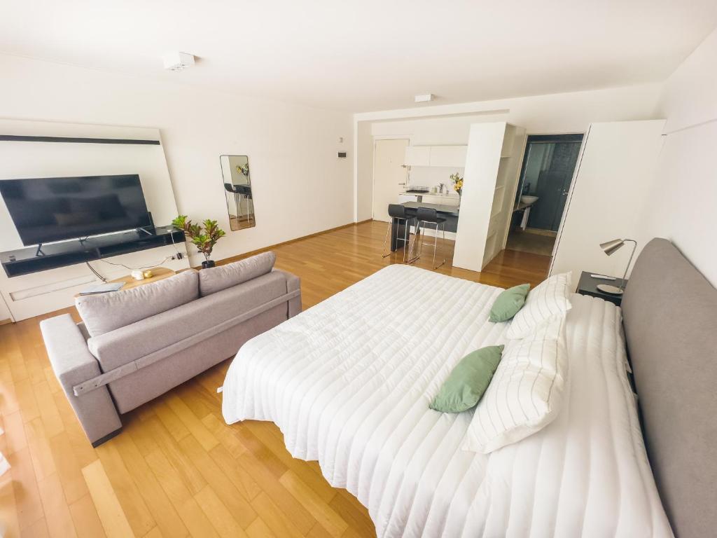 ein Schlafzimmer mit einem großen weißen Bett und einem Sofa in der Unterkunft Recoleta Tower House in Buenos Aires