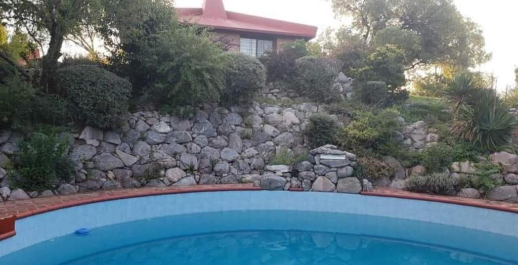 a swimming pool in front of a stone wall at Terrazas del Venado in La Cumbre