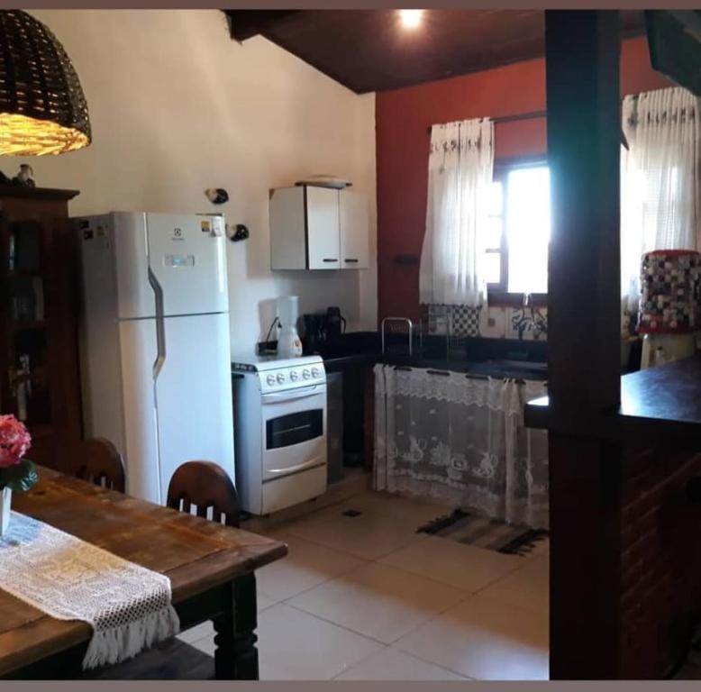 a kitchen with a white refrigerator and a table at Sossego entre as montanhas de Itaipava in Petrópolis