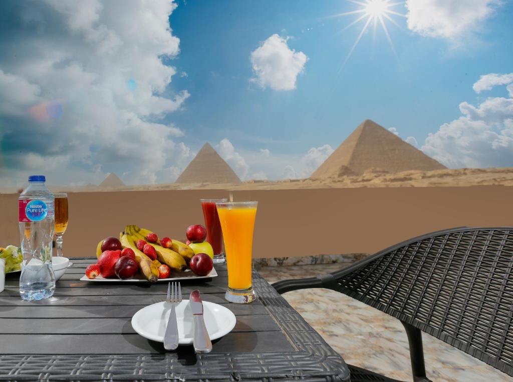 un tavolo con un piatto di frutta e un bicchiere di succo d'arancia di Sky Pyramids View Inn a Il Cairo