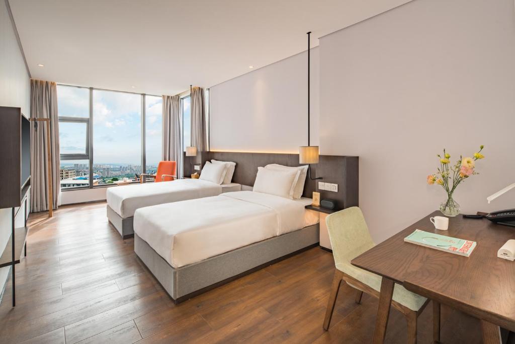 a hotel room with a bed and a desk and a table at Wuyu Hotel - Chongqing Jiangbei Airport & Light Rail in Chongqing