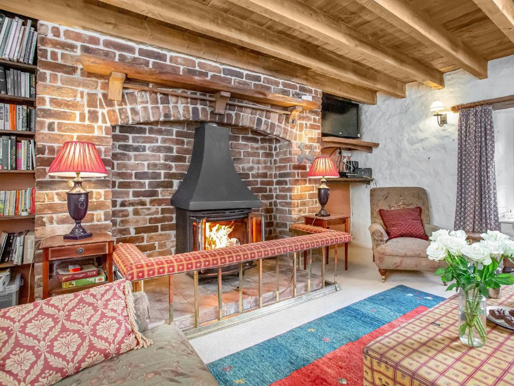 a living room with a brick fireplace with a fire place at Hallowarren Barn in Saint Anthony