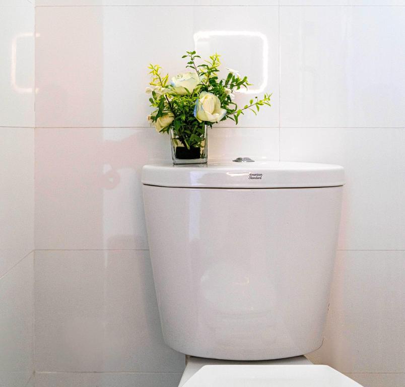 a white toilet with a vase of flowers on it at Wuyu Hotel - Chongqing Jiangbei Airport & Light Rail in Chongqing