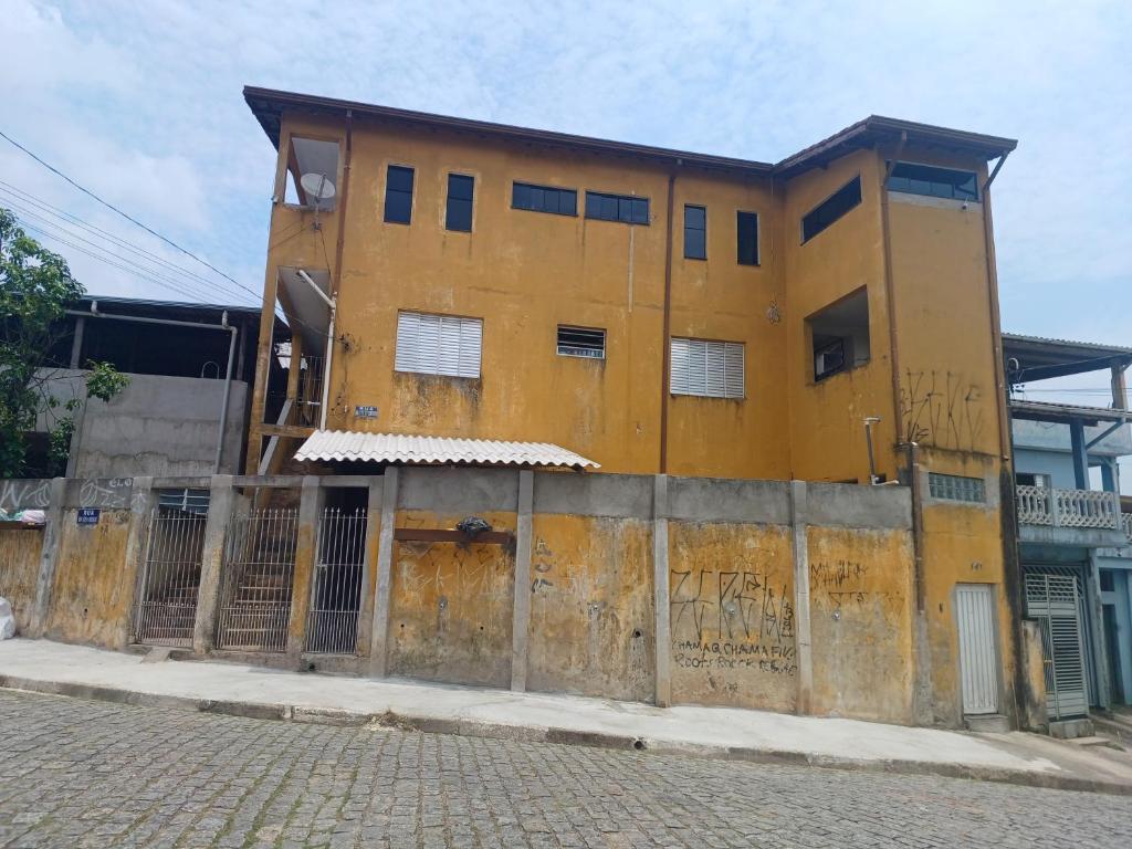 un viejo edificio amarillo al lado de una calle en Ro Rooms, en Rio Grande da Serra