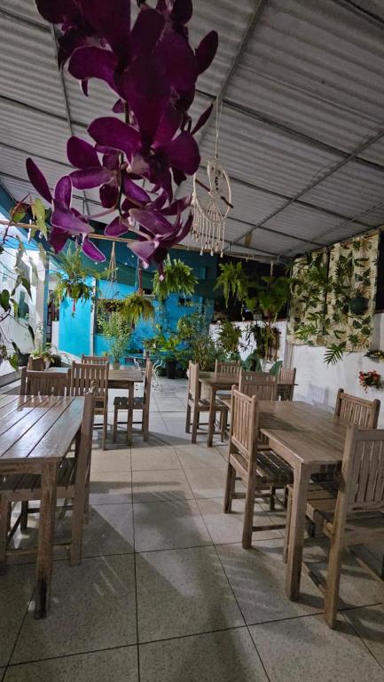 un restaurante con mesas y bancos de madera y flores púrpuras en Pousada Mikaela Arraial, en Arraial d'Ajuda