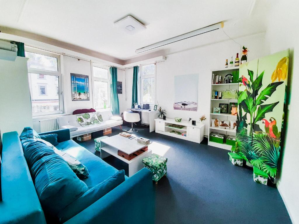 a living room with a blue couch and some windows at Goethes Haus in Göttingen