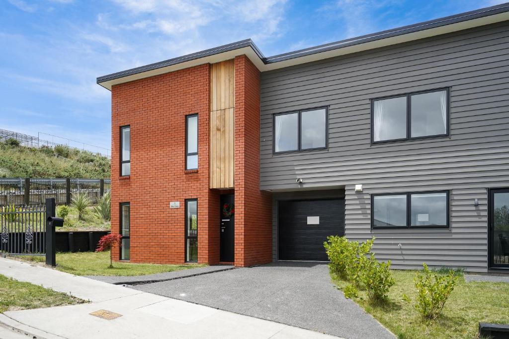 uma casa de tijolos vermelhos com uma garagem preta em Stunning 3 bedrooms house in Hillcrest - Close to Waikato University & Cambridge em Hamilton