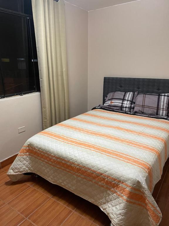 a bedroom with a bed with an orange and white comforter at Hostal Alborada in Cajamarca