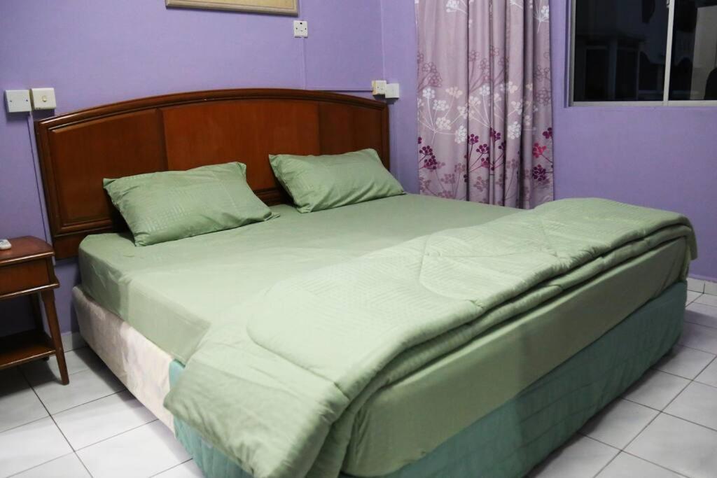 a bedroom with a large bed with a wooden headboard at Kuhara Court Apartment Suite in Tawau