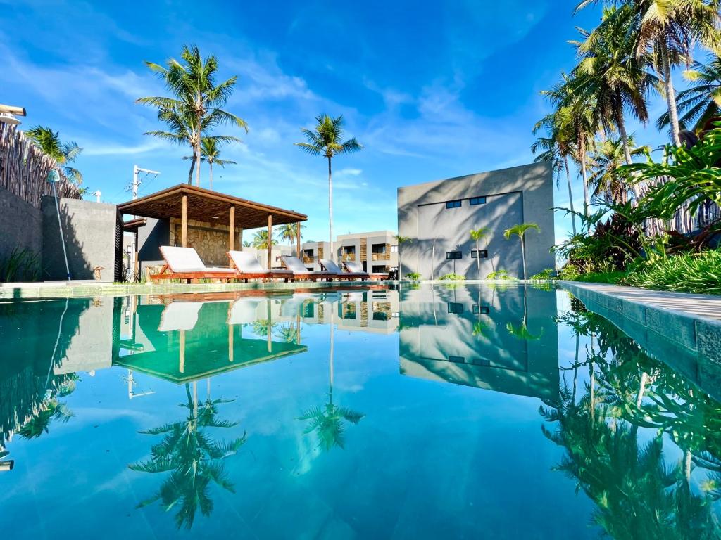 a swimming pool with palm trees and a house at Casa Salga Patacho F003 - Rota Ecológica de São Miguel dos Milagres in Pôrto de Pedras