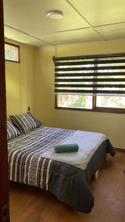 um quarto com uma cama e duas janelas em Hostal Pelluco em Llanquihue