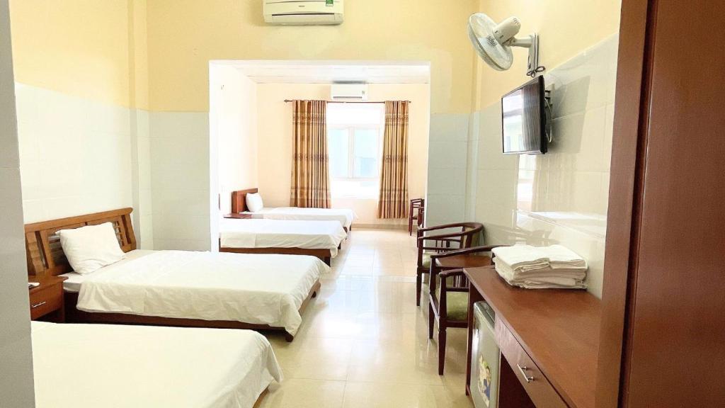 um quarto com três camas e uma mesa e cadeiras em Khách sạn 206 em Da Nang