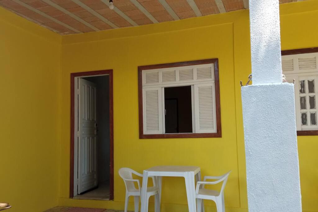 a yellow wall with a table and chairs in a room at Suíte em Cumuruxatiba beira-mar in Cumuruxatiba