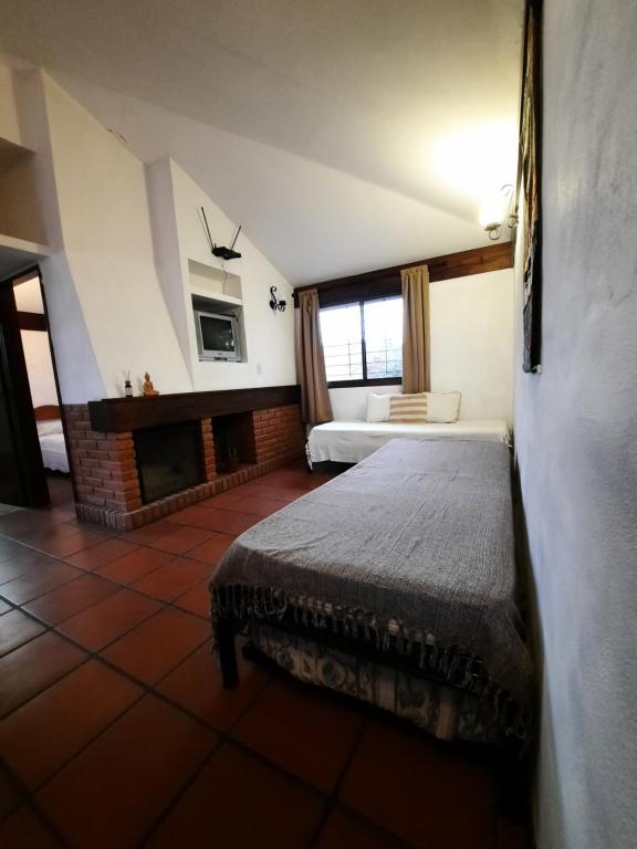 une chambre d'hôtel avec un lit et une cheminée dans l'établissement Terrazas del Venado, à La Cumbre