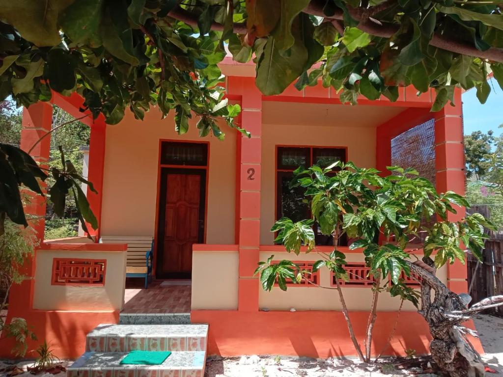 una casa con una porta rossa e un albero di Ocean Holiday liukang a Bira