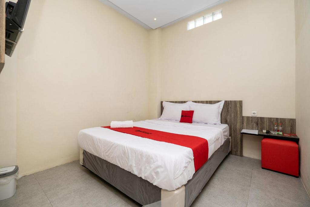 um quarto com uma cama grande e um cobertor vermelho em RedDoorz @ Sangnala Homestay Pakisaji em Malang