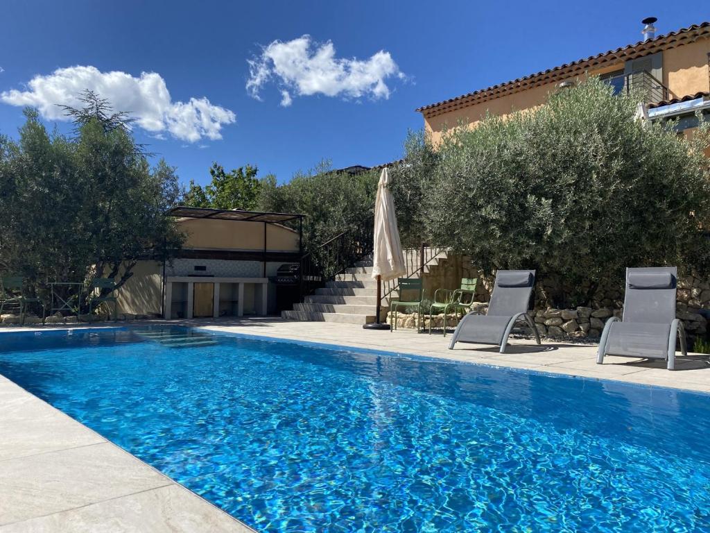 - une piscine avec des chaises et un parasol à côté d'une maison dans l'établissement Grande villa rénovée avec piscine, clim et Wi-Fi au coeur du Luberon - FR-1-708-61, à Saint-Saturnin-lès-Apt