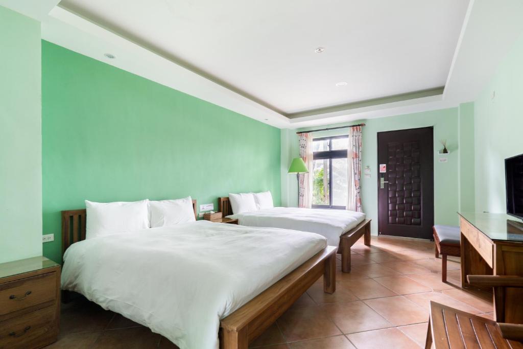 two beds in a room with green walls and a tv at Songyuan 68 Villa in Hualien City