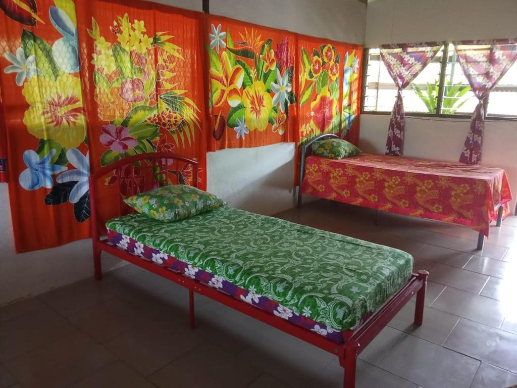 a room with two beds in a room with paintings at Ravehei smile relais 3 Huahine in Haapu