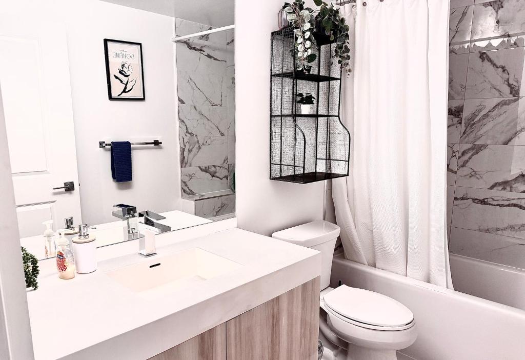 Baño blanco con lavabo y aseo en Cozy 2 Bedroom by Eaton Centre Mall, en Toronto