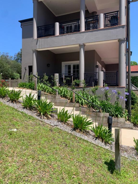 una casa con plantas delante de ella en The Grande Port Stephens Luxurious golf and beach getaway on Horizons Golf Resort, en Salamander Bay