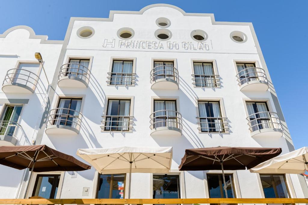 un edificio blanco con sombrillas delante en Princesa do Gilão en Tavira