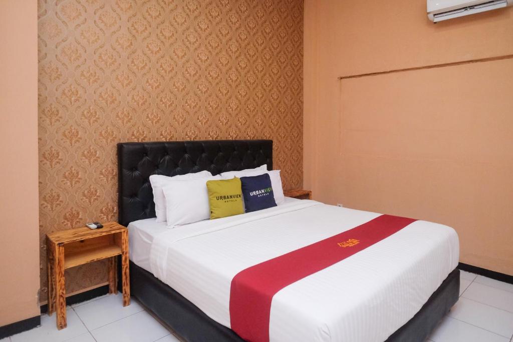 a bedroom with a large bed with a black headboard at Urbanview Hotel L'Tefa Pemalang 