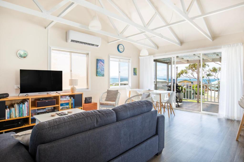 a living room with a couch and a tv at Seahaven - Pet Friendly with Ocean Views- 2 Mins to Beach in Currarong