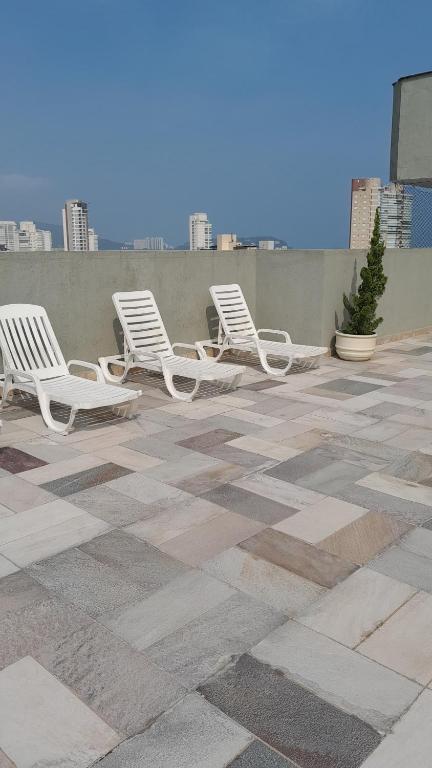 a row of white chairs sitting on a patio at Biwa Edifício cm Piscina, WI-FI, 1 garagem , Portaria 24hs,churrasqueira, Playground, Jardim, Centro do Guarujá, próximo do Comércio e da Praia in Guarujá