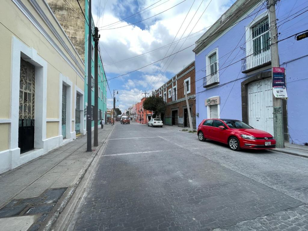 a red car parked on the side of a street at Céntrico Aparta Hotel, #3 Privado, ideal familias o trabajo in Puebla