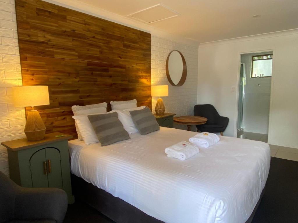 a bedroom with a large white bed with a wooden headboard at Beachmere Palms Motel in Beachmere